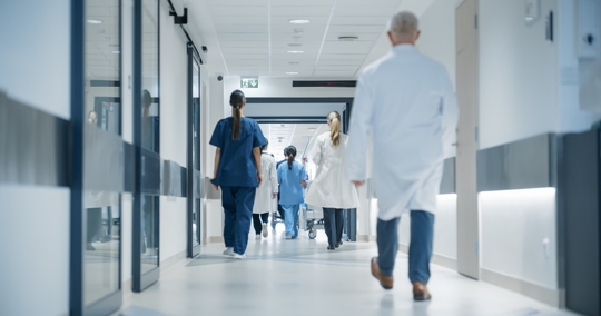 Hospital Hallway with Doctors, Nurses and Specialists in Hospital. Female and Male Physicians, Surgeons, Healthcare Officials Walk Together in Corridor with Their Back to Camera stock photo